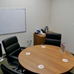 A small meeting room space with seating for 4x individuals and a whiteboard on the wall.