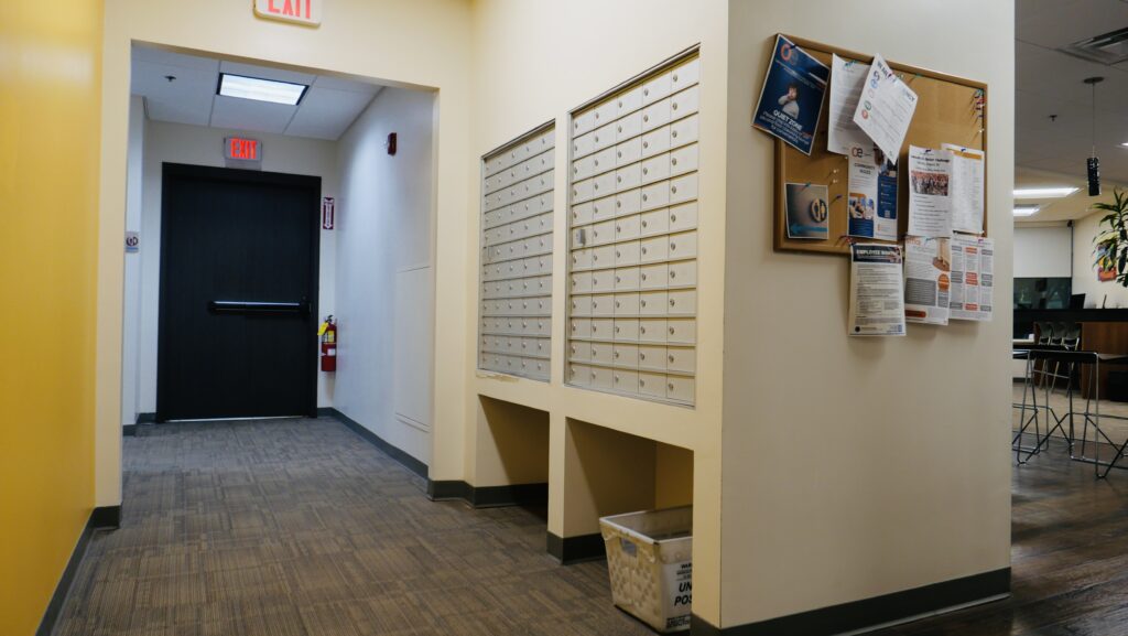 Wall mounted mailboxes along a long office hallway.