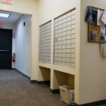 Wall mounted mailboxes along a long office hallway.